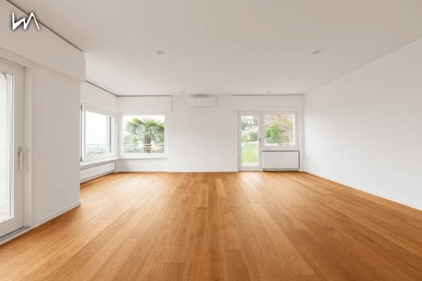 An empty living room with bare wooden floors and white walls, before virtual staging.